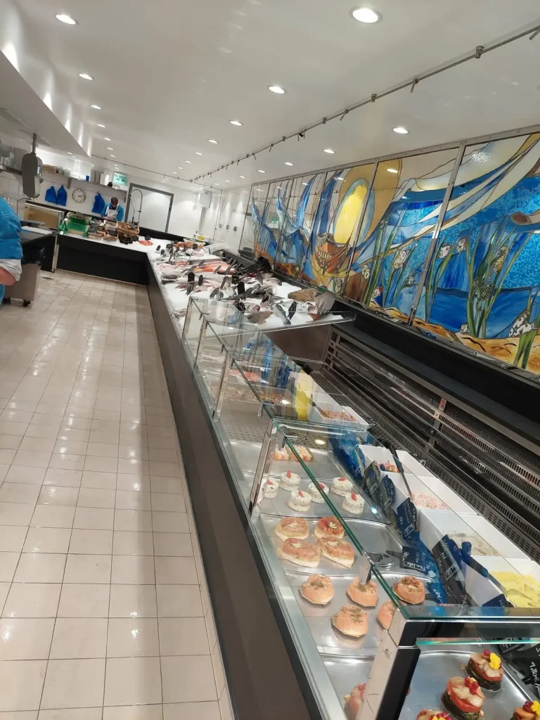 Étal de la poissonnerie La Sablaise en activité, sous le vitrail décoratif