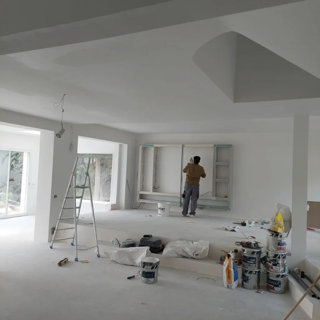 Compagnon PFM Bâtiment montant l’ossature de la niche télévision dans l’extension
