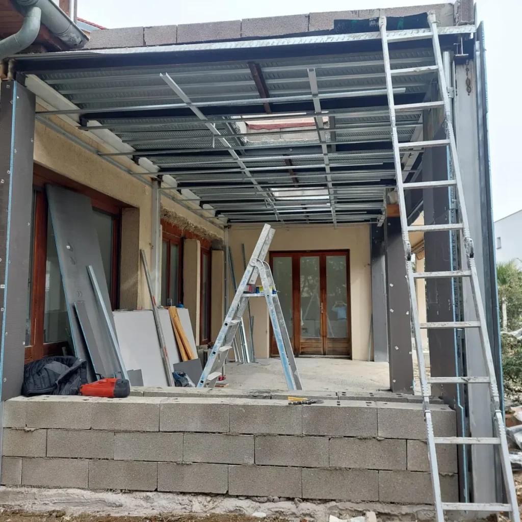 Ossature métallique de la couverture de l’extension posée sur les murs en parpaing