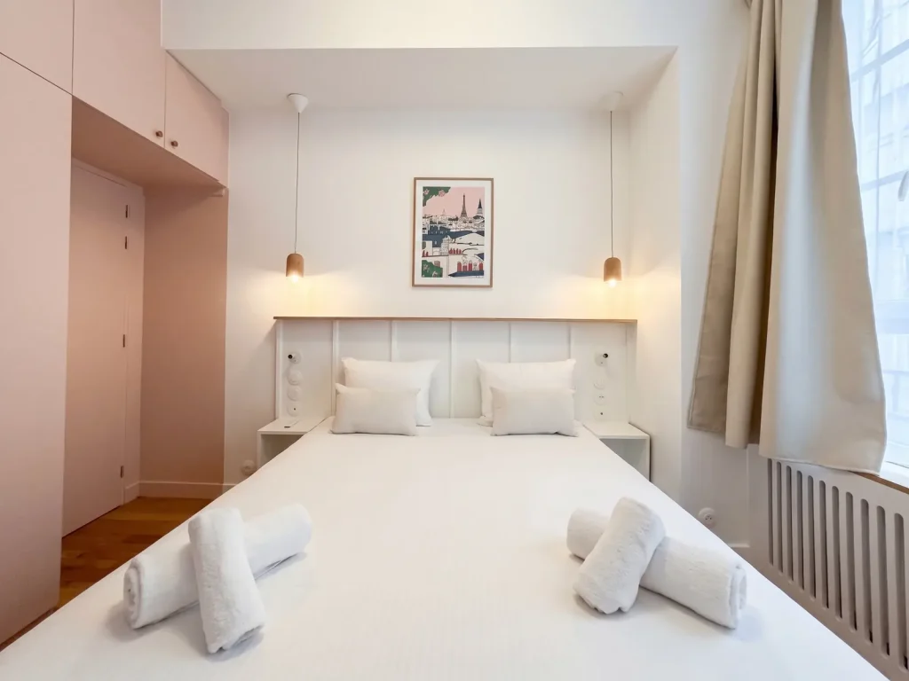 Chambre rénovée de l’appartement Lathuille, tête de lit sur-mesure et liseuses suspendues